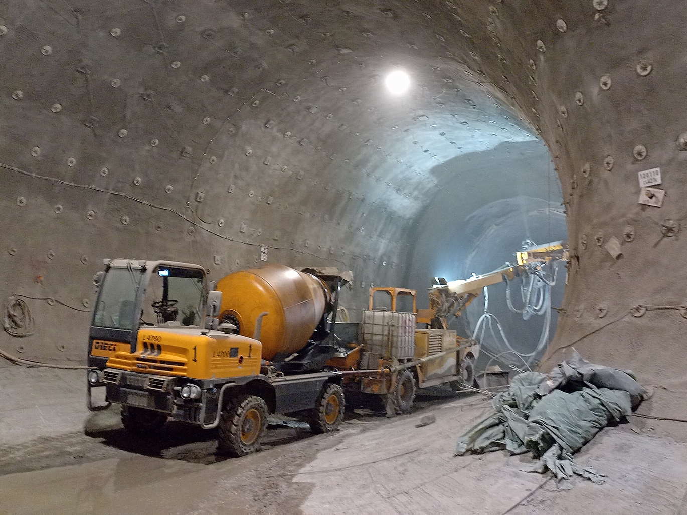 Man sieht ein Baufahrzeugt, welches grade den Tunnel mit einer Betonmsichung auskleidet.